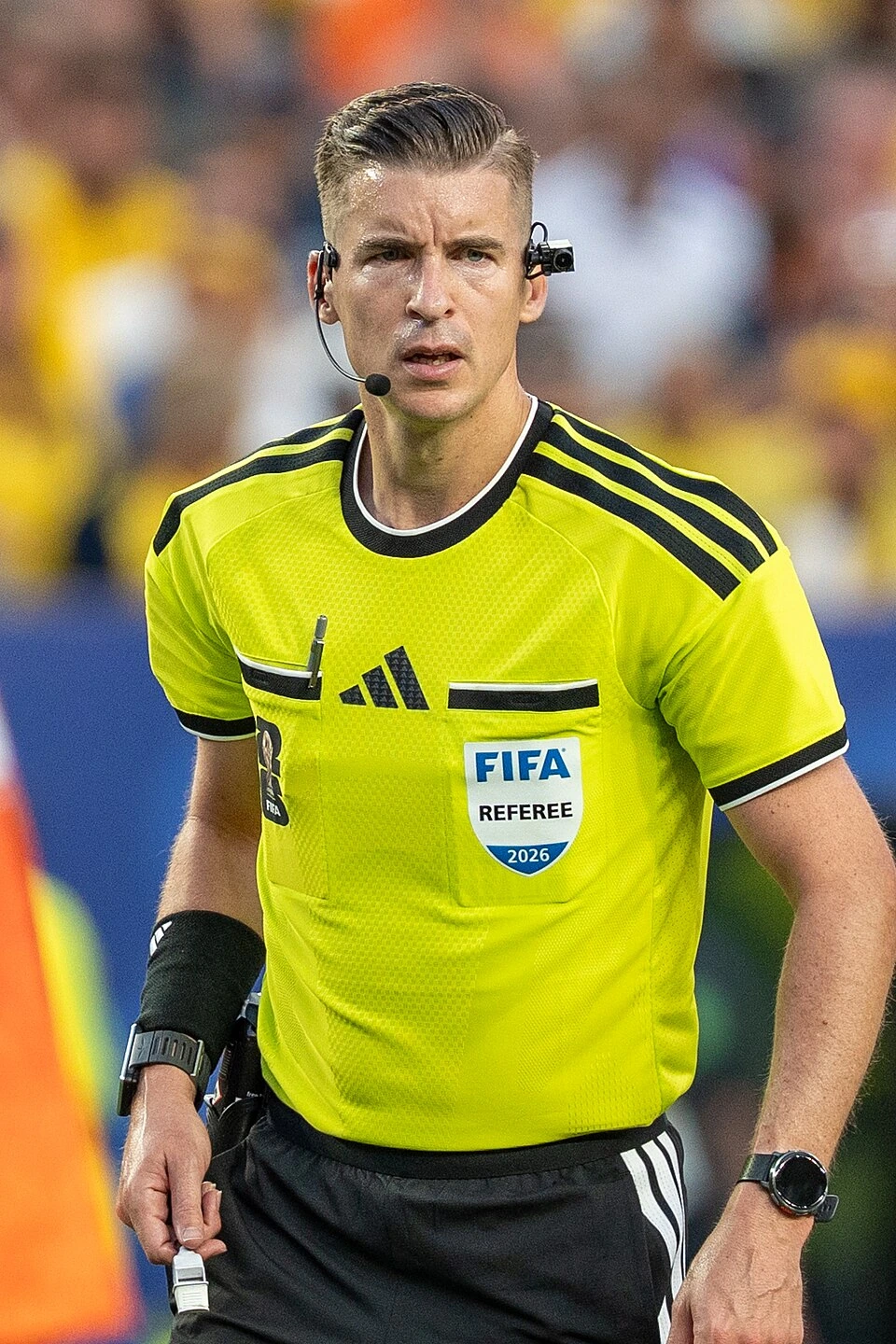 François Letexier refereeing a football match in a bright yellow FIFA referee shirt